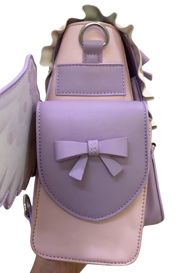 A pastel lavender and light pink shoulder bag with a bow on the front flap, shown being held against a plain white background.
